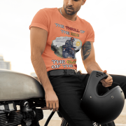 Medium-sized coral Thrill Rider tee featuring a high-energy motorbike rider against a scenic outdoor backdrop. The bold typography and adventurous design make this an ideal tee for motorcycle lovers and thrill-seekers.