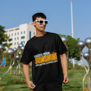 Stylish black oversized T-shirt with a motivational quote 'CREATE YOUR SUNSHINE EVEN ON THE CLOUDIEST DAYS.' Contrasting sky-blue, orange/yellow, and white text with a sun icon. DTG-printed on premium 240 GSM cotton fabric. Large size.