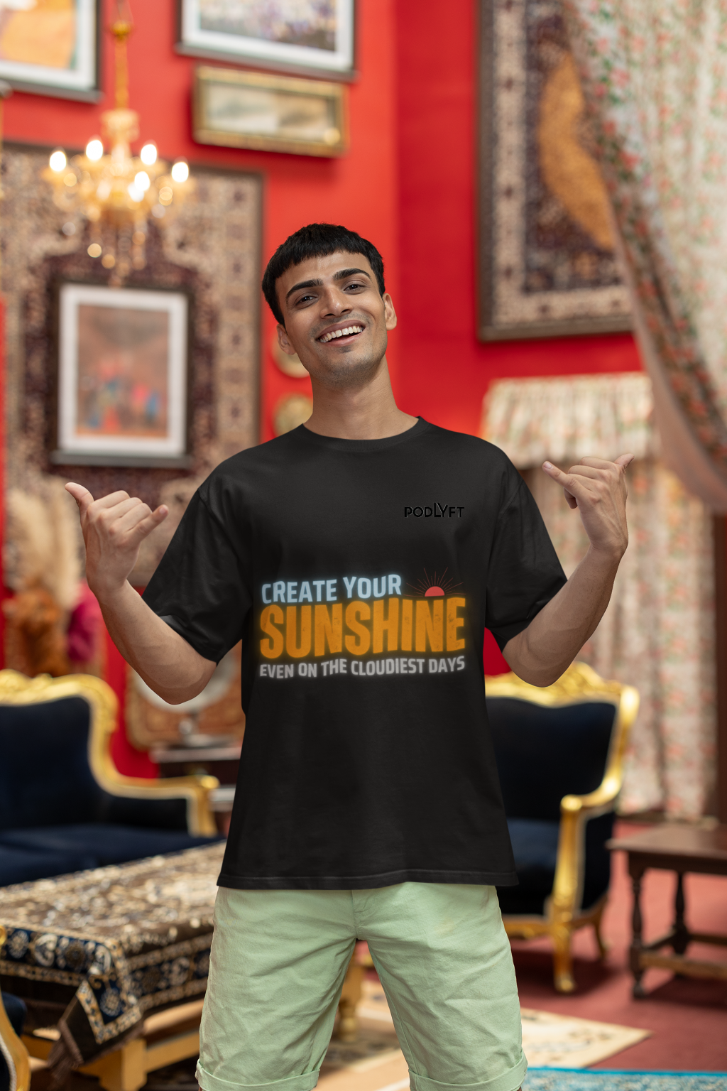 Motivational black oversized T-shirt with a bold 'CREATE YOUR SUNSHINE EVEN ON THE CLOUDIEST DAYS' design. Vibrant sky-blue, orange/yellow, and white text with a sun icon. DTG-printed on durable 240 GSM cotton fabric. Small size.