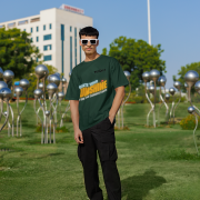 Bottle green oversized T-shirt with a motivational 'CREATE YOUR SUNSHINE EVEN ON THE CLOUDIEST DAYS' design. Bright sky-blue, orange/yellow, and white text with a sun icon. DTG-printed on durable 240 GSM cotton fabric. Double Extra Large size.