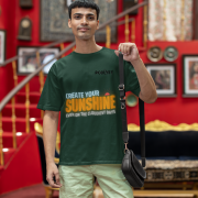 Bottle green oversized T-shirt featuring a motivational design with 'CREATE YOUR SUNSHINE EVEN ON THE CLOUDIEST DAYS' in sky-blue, warm orange/yellow, and white text. Includes a sun icon, printed using DTG on premium 240 GSM cotton fabric. Extra Small size.