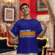 Motivational navy blue oversized T-shirt with a bold 'CREATE YOUR SUNSHINE EVEN ON THE CLOUDIEST DAYS' design. Vibrant sky-blue, orange/yellow, and white text with a sun icon. DTG-printed on durable 240 GSM cotton fabric. Small size.