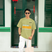 Olive green oversized tee with a bright and uplifting 'CREATE YOUR SUNSHINE EVEN ON THE CLOUDIEST DAYS' design. Features sky-blue, orange/yellow, and white text with a sun icon. DTG-printed on soft 240 GSM cotton fabric. Medium size