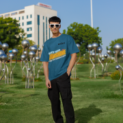 Petrol blue oversized T-shirt with a motivational 'CREATE YOUR SUNSHINE EVEN ON THE CLOUDIEST DAYS' design. Bright sky-blue, orange/yellow, and white text with a sun icon. DTG-printed on durable 240 GSM cotton fabric. Double Extra Large size.