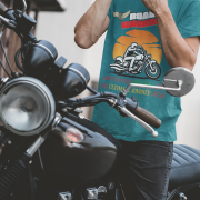 Petrol blue Road Warrior tee in small size, designed for bikers who embrace the open road. The striking motorcyclist silhouette, bold typography, and adventurous sunset backdrop create a powerful and stylish biker statement.