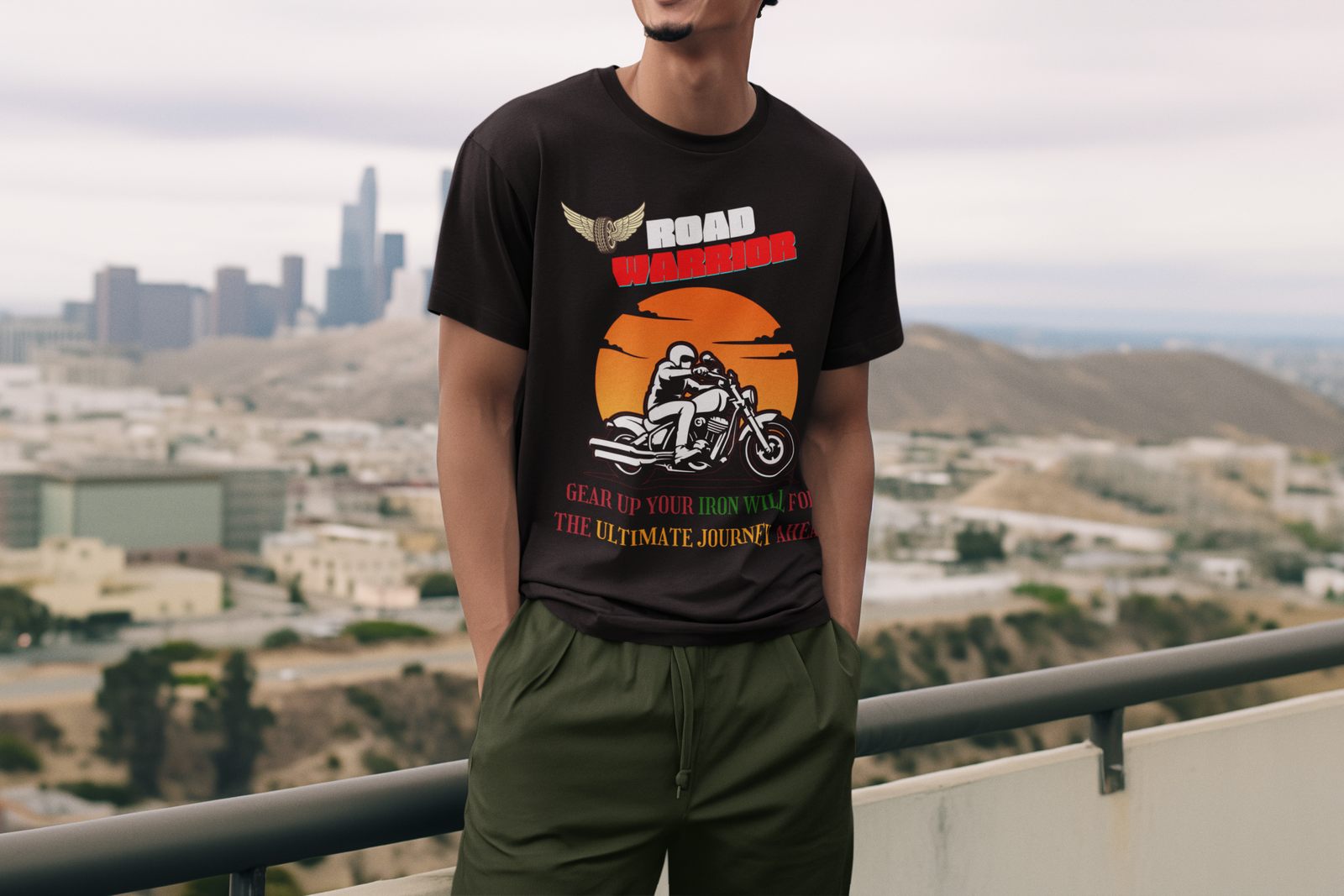 A stylish man wearing the black Road Warrior tee with a city skyline in the background. The graphic tee showcases a striking biker design, bold typography, and an energetic sunset, making it an ideal choice for passionate riders who embrace the thrill of the open road.