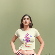 Model styled in a warm beige 'Bloom Yourself' T-shirt, enhanced by a delicate floral and butterfly design. A natural and sophisticated wardrobe addition, available at PodLyft