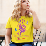 Model styled in a radiant golden yellow 'Bloom Yourself' T-shirt, adorned with a striking floral and butterfly design. A cheerful and uplifting wardrobe essential, available at PodLyft.
