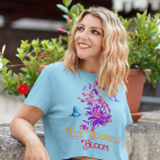 Model wearing a refreshing sky blue 'Bloom Yourself' T-shirt with a bold floral and butterfly design. A light and airy fashion piece, available at PodLyft.