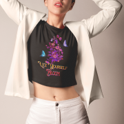 Confident woman wearing a stylish black crop top with a bold 'Bloom Yourself Tee' floral and butterfly design. She pairs it with a chic white blazer and shorts, creating a modern and fashionable look. Available at PodLyft.