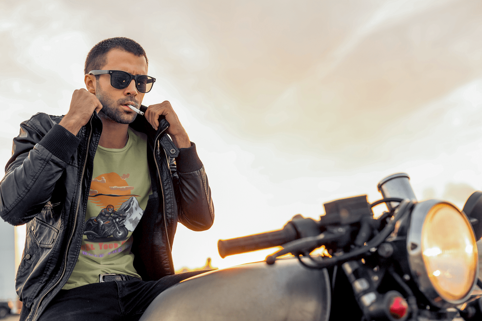 A man in a black jacket poses confidently, showcasing a bold biker graphic tee featuring adventure motorcycle art.