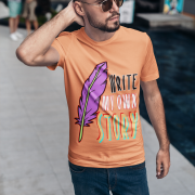 A bright coral Write Your Story Tee with an uplifting message and a striking feather quill design. Perfect for self-motivated individuals and creatives. High-quality cotton by PodLyft.