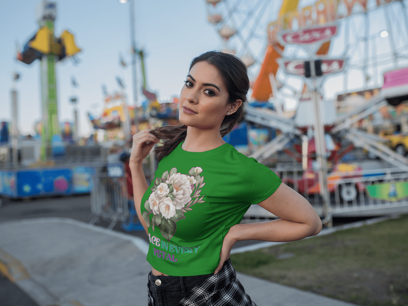 Grace in Every Petal Tee – A stylish green floral crop top adorned with a delicate white rose bouquet design, worn by a confident model at a vibrant carnival. A perfect fusion of elegance and casual flair.