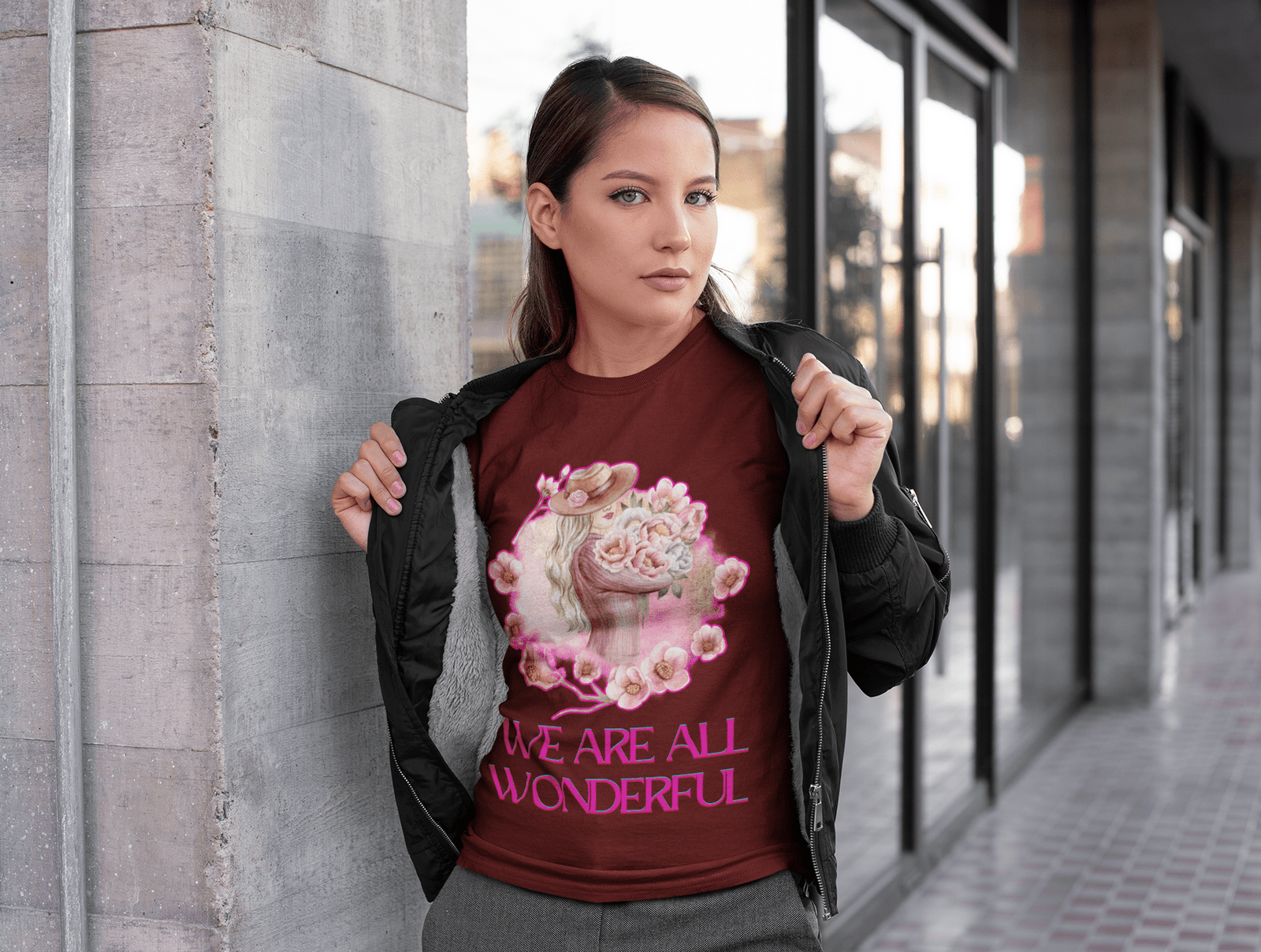 A confident woman showcasing the Maroon 'Inspirational Floral Tee - We Are All Wonderful' by PodLyft, featuring an elegant design of a woman in a hat surrounded by delicate pink flowers. A stylish statement of positivity and empowerment.