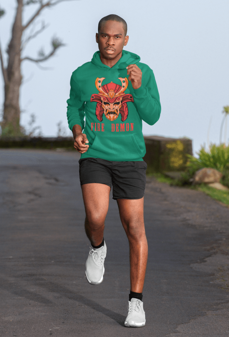 Men’s Fire Demon Samurai Hoodie by PodLyft in bottle green, on a mannequin, featuring a bold red and orange samurai helmet design with a demonic face and 'FIRE DEMON' text, displayed in a modern store with blurred clothing racks in the background.