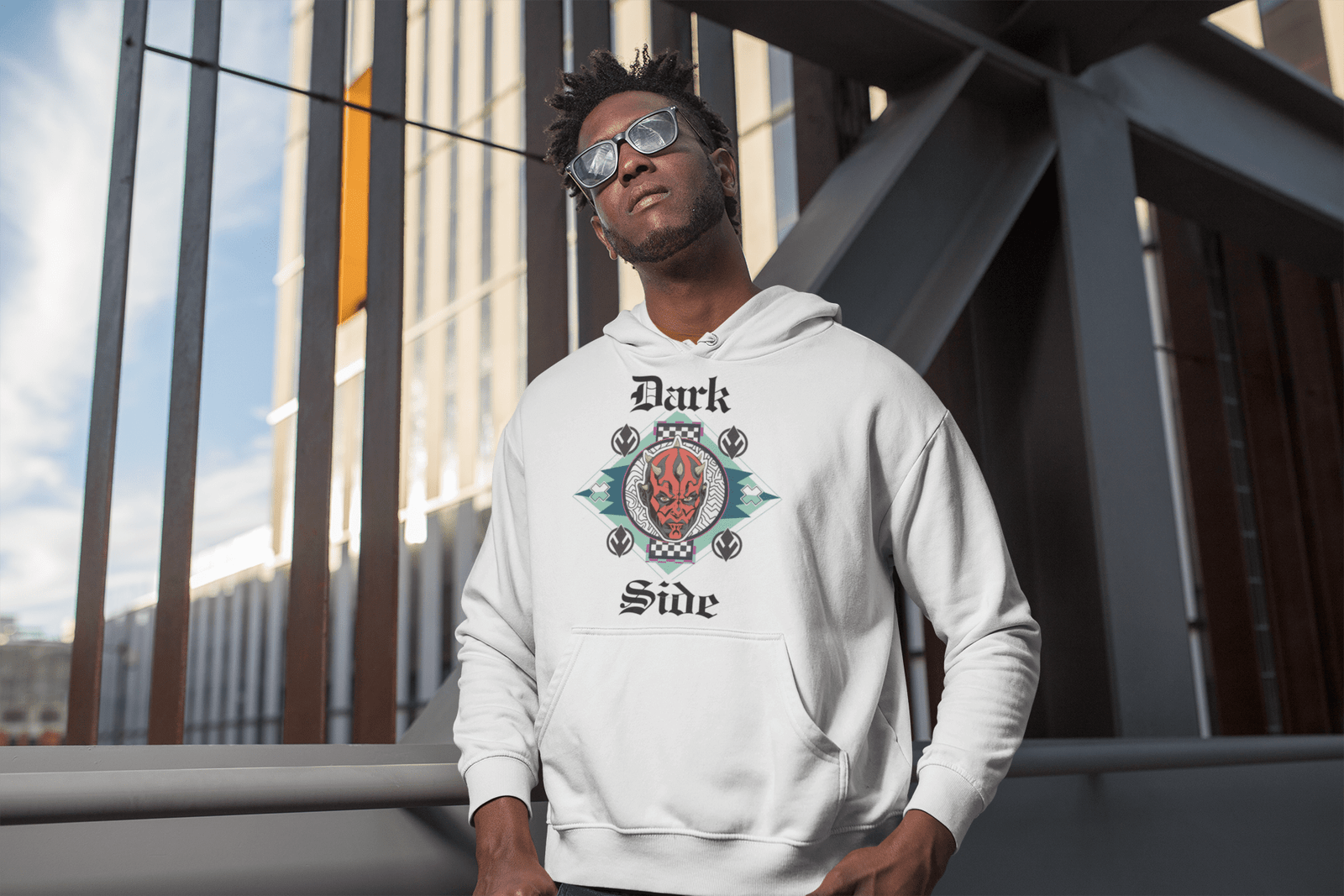 Model wearing a white 'Official Darth Maul Hoodie' by PodLyft, featuring a red-and-black Darth Maul graphic with yellow eyes, framed in a teal and mint green diamond pattern, with 'Dark' and 'Side' in gothic white text, standing on a balcony overlooking a city skyline at dusk.