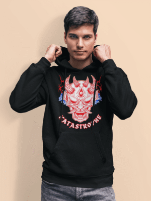 Man wearing a black Catastrophe Demon Graphic Hoodie featuring a bold red and white demon face graphic with horns and fangs, surrounded by blue flames and the word "CATASTROPHE" in stylized text; streetwear design by PodLyft.