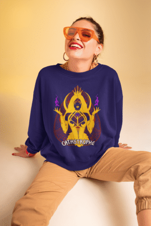 Woman wearing the PodLyft Women's Catastrophe Mystic Sweatshirt in deep purple, featuring a bold mystical enchantress design in gold and red with glowing purple flames, sitting against a soft beige background while smiling confidently.