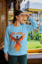 A young woman, possibly of Caucasian descent with light brown hair, wearing a baby blue PodLyft women's Fire Within sweatshirt. The sweatshirt features a graphic of a human heart with stylized flames emanating from its top, and the text "FIRE WITHIN" written above and below it. She is looking directly at the camera with a subtle smile, standing against a plain light grey background.