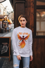 A young woman, possibly of Caucasian descent with light brown hair, wearing a lavender PodLyft women's Fire Within sweatshirt. The sweatshirt features a graphic of a human heart with stylized flames emanating from its top, and the text "FIRE WITHIN" written above and below it. She is looking directly at the camera with a subtle smile, standing against a plain light grey background.