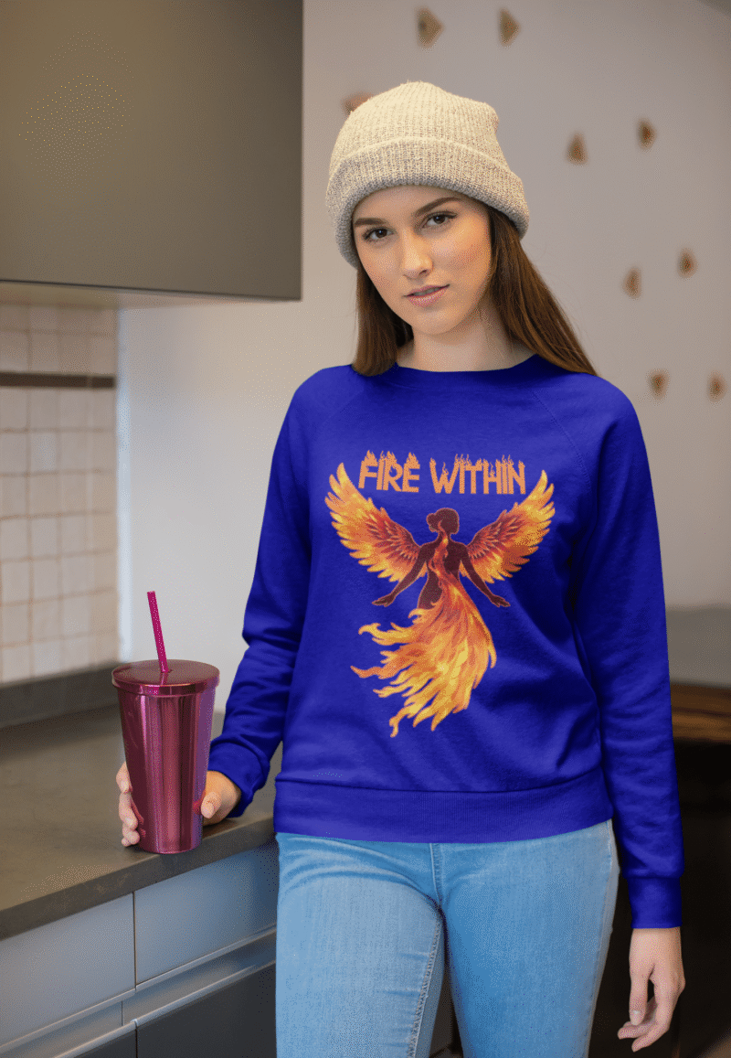 A young woman, possibly of Caucasian descent with light brown hair, wearing a navy blue PodLyft women's Fire Within sweatshirt. The sweatshirt features a graphic of a human heart with stylized flames emanating from its top, and the text "FIRE WITHIN" written above and below it. She is looking directly at the camera with a subtle smile, standing against a plain light grey background.