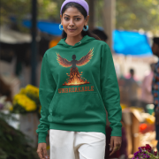 A young woman, possibly of Caucasian descent, with dark hair tied back, wearing a bottle green PodLyft women's Unbreakable Spirit hoodie. The hoodie features a graphic of a stylized, strong female figure in motion, with the word "UNBREAKABLE" across her. She is looking directly at the camera with a determined expression, standing against a plain light grey background.