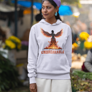 A young woman, possibly of Caucasian descent, with dark hair tied back, wearing a lavender PodLyft women's Unbreakable Spirit hoodie. The hoodie features a graphic of a stylized, strong female figure in motion, with the word "UNBREAKABLE" across her. She is looking directly at the camera with a determined expression, standing against a plain light grey background.