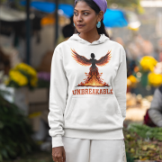 A young woman, possibly of Caucasian descent, with dark hair tied back, wearing a white PodLyft women's Unbreakable Spirit hoodie. The hoodie features a graphic of a stylized, strong female figure in motion, with the word "UNBREAKABLE" across her. She is looking directly at the camera with a determined expression, standing against a plain light grey background.