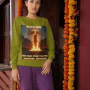 A young woman, possibly of South Asian descent, with long dark hair, wearing an olive green PodLyft Yagyaseni Fireborn sweatshirt. The sweatshirt features a stylized graphic of a woman's silhouette against a fiery, abstract background, with the text "YAGYASENI" written below. She is looking directly at the camera with a confident expression, her arms crossed, standing against a plain light grey background.