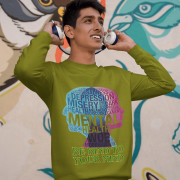 A young man, possibly of Caucasian descent, with short dark hair and a beard, wearing an olive green PodLyft Mental Wellness Sweatshirt for men. The sweatshirt features a circular graphic with the letters "BKTYM" prominently in the center, surrounded by the phrase "BE KIND TO YOUR MIND." He is looking directly at the camera with a confident expression, standing against a plain light grey background.