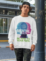 A young man, possibly of Caucasian descent, with short dark hair and a beard, wearing a white PodLyft Mental Wellness Sweatshirt for men. The sweatshirt features a circular graphic with the letters "BKTYM" prominently in the center, surrounded by the phrase "BE KIND TO YOUR MIND." He is looking directly at the camera with a confident expression, standing against a plain light grey background.
