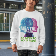 A young man, possibly of Caucasian descent, with short dark hair and a beard, wearing a white PodLyft Mental Wellness Sweatshirt for men. The sweatshirt features a circular graphic with the letters "BKTYM" prominently in the center, surrounded by the phrase "BE KIND TO YOUR MIND." He is looking directly at the camera with a confident expression, standing against a plain light grey background.