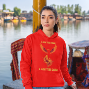 A young woman, possibly of Caucasian descent, with light brown hair pulled back, wearing a red PodLyft Women's Revolution Hoodie. The hoodie features a graphic of a stylized, strong female figure, with the text "I AM THE FIRE I AM THE REVOLUTION" below it. She is looking directly at the camera with a confident expression, standing against a plain light grey background.