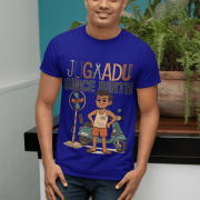 A young man, possibly of Caucasian descent, with short dark hair and a beard, wearing a navy blue PodLyft Men's Jugaadu t-shirt. The t-shirt features a graphic with the text "JUGAADU SINCE BIRTH." He is looking directly at the camera with a confident expression, standing against a plain light grey background.