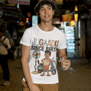 A young man, possibly of Caucasian descent, with short dark hair and a beard, wearing a white PodLyft Men's Jugaadu t-shirt. The t-shirt features a graphic with the text "JUGAADU SINCE BIRTH." He is looking directly at the camera with a confident expression, standing against a plain light grey background.