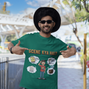 A young man, possibly of Caucasian descent, with short dark hair and a beard, wearing a bottle green t-shirt. The t-shirt features a humorous graphic with the Hindi text "SCENE KYA HAI" and a stylized question mark. He is looking directly at the camera with a confident expression, standing against a plain light grey background.