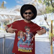 A young man, possibly of Caucasian descent, with short dark hair and a beard, wearing a maroon PodLyft Pataka t-shirt. The t-shirt features a flirty graphic with the text, "Girl, were you born on Diwali? Because You are PATAKA." He is looking directly at the camera with a confident expression, standing against a plain light grey background.
