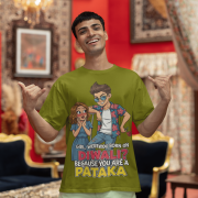 A young man, possibly of Caucasian descent, with short dark hair and a beard, wearing an olive green PodLyft Pataka t-shirt. The t-shirt features a flirty graphic with the text, "Girl, were you born on Diwali? Because You are PATAKA." He is looking directly at the camera with a confident expression, standing against a plain light grey background.