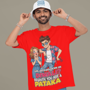 A young man, possibly of Caucasian descent, with short dark hair and a beard, wearing a red PodLyft Pataka t-shirt. The t-shirt features a flirty graphic with the text, "Girl, were you born on Diwali? Because You are PATAKA." He is looking directly at the camera with a confident expression, standing against a plain light grey background.