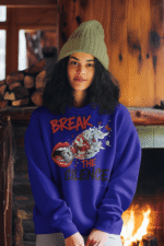 A young woman, possibly of Caucasian descent, with light brown hair pulled back, wearing a navy blue PodLyft Women's Break the Silence Hoodie. The hoodie features a graphic of a padlocked mouth with doves and butterflies bursting out, and the text "BREAK THE SILENCE" and "RAISE YOUR VOICE." She is looking directly at the camera with a confident expression, standing against a plain light grey background.