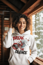 A young woman, possibly of Caucasian descent, with light brown hair pulled back, wearing a white PodLyft Women's Break the Silence Hoodie. The hoodie features a graphic of a padlocked mouth with doves and butterflies bursting out, and the text "BREAK THE SILENCE" and "RAISE YOUR VOICE." She is looking directly at the camera with a confident expression, standing against a plain light grey background.