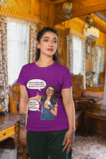 A woman wearing a purple PodLyft Girls Savage Queen Tee with a funny graphic and Hindi text. She is standing indoors in a cozy, wood-paneled room. The graphic features a woman giving a thumbs-up, with text bubbles that translate to "If a guy proposes to me, I reject him" and "But I salute his choice.
