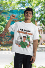 A man smiling in a white PodLyft Men's Engineering Stress Tee outdoors with a wall mural in the background. The graphic on the shirt shows a stressed-out male engineer surrounded by broken electronics, wires, and coffee, with the Hindi text "MAA KASAM ENGINEER HOON" and a book titled "LEARN PYTHON 7 DAYS!