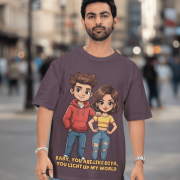 A young man with short dark hair and a beard, wearing a black PodLyft oversized Light Up T-shirt. The t-shirt features a graphic of a cartoon-style couple and the flirty text, "Baby You Are Like Diya, You Light Up My World." He is looking directly at the camera with a confident expression, standing against a plain light grey background.