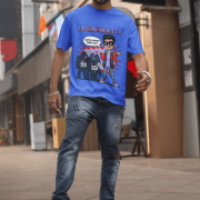 A young man, possibly of Caucasian descent, with short dark hair and a beard, wearing a royal blue PodLyft Log Kya Kahenge T-shirt. The t-shirt features a funny social parody graphic with Hindi text. He is looking directly at the camera with a confident expression, standing against a plain light grey background.