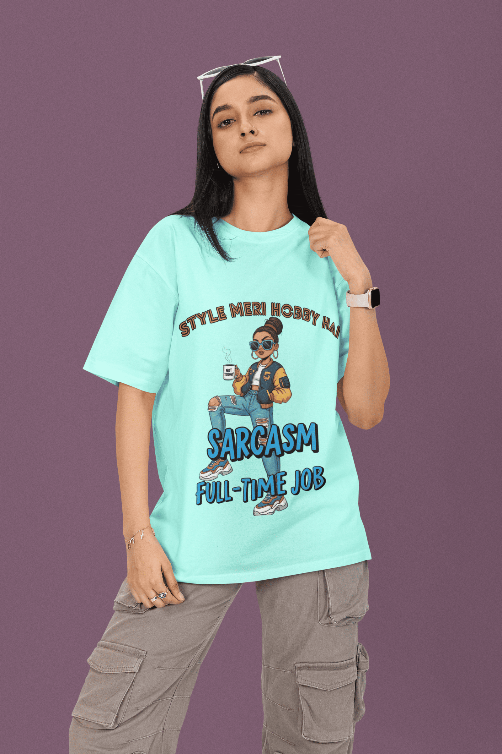 Woman wearing PodLyft Women's Full-Time Sarcasm Tee in mint green featuring cartoon character design with 'Style Meri Hobby Hai' and 'Sarcasm Full-Time Job' text, paired with gray cargo pants against purple background