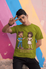 PodLyft Cheesy Pickup Line T-shirt in olive green, worn by a man making a peace sign against a colorful striped wall. The shirt features the 'Tu Cheese Badi Hai Mast Mast' pizza pickup line design.