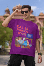 A man wearing a purple PodLyft Men's Procrastinator Gym Tee, smiling and adjusting his sunglasses outdoors in front of a classical building. The graphic shows a cartoon man relaxing on a couch surrounded by junk food, with the Hindi text "KAL SE PAKKA GYM!" and a TV screen saying "MOTIVATIONAL WORKOUT: 4 HOURS LEFT TO START."