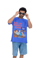 A man wearing a royal blue PodLyft Men's Procrastinator Gym Tee against a solid dark green background, adjusting his blue sunglasses. The graphic shows a cartoon man relaxing on a couch surrounded by junk food, with the Hindi text "KAL SE PAKKA GYM!" and a TV screen saying "MOTIVATIONAL WORKOUT: 4 HOURS LEFT TO START.