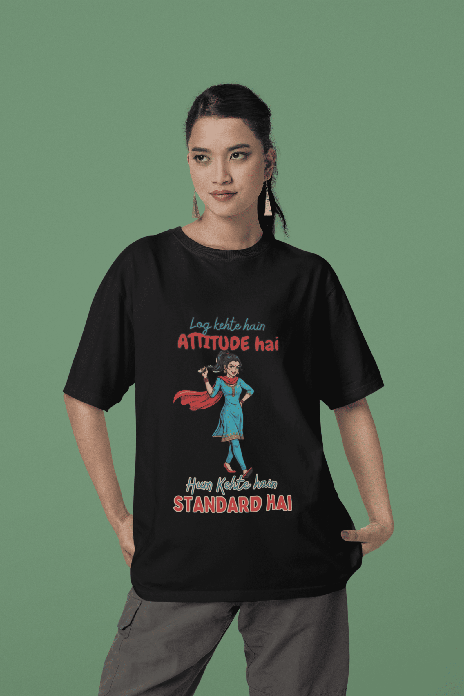 Black Desi Swag Oversized Tee by PodLyft. A model wears a black t-shirt featuring a confident Desi girl illustration and the Hindi text "Log kehte hain ATTITUDE hai, Hum Kehte hain STANDARD HAI."